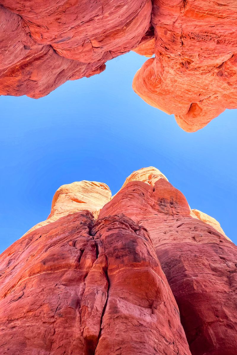 Looking up at the towering red rock formations of Cathedral Rock, framed against a vibrant blue sky.