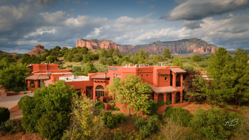 A vibrant view of Sedona's stunning red rock formations, framed by lush greenery and the charming adobe-style architecture of Las Posadas.