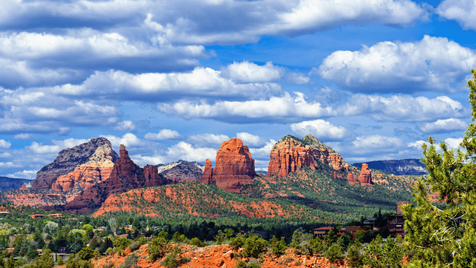 A breathtaking view of Sedona's iconic red rock formations under a sky filled with fluffy clouds, showcasing the stunning landscape and natural beauty of the area.