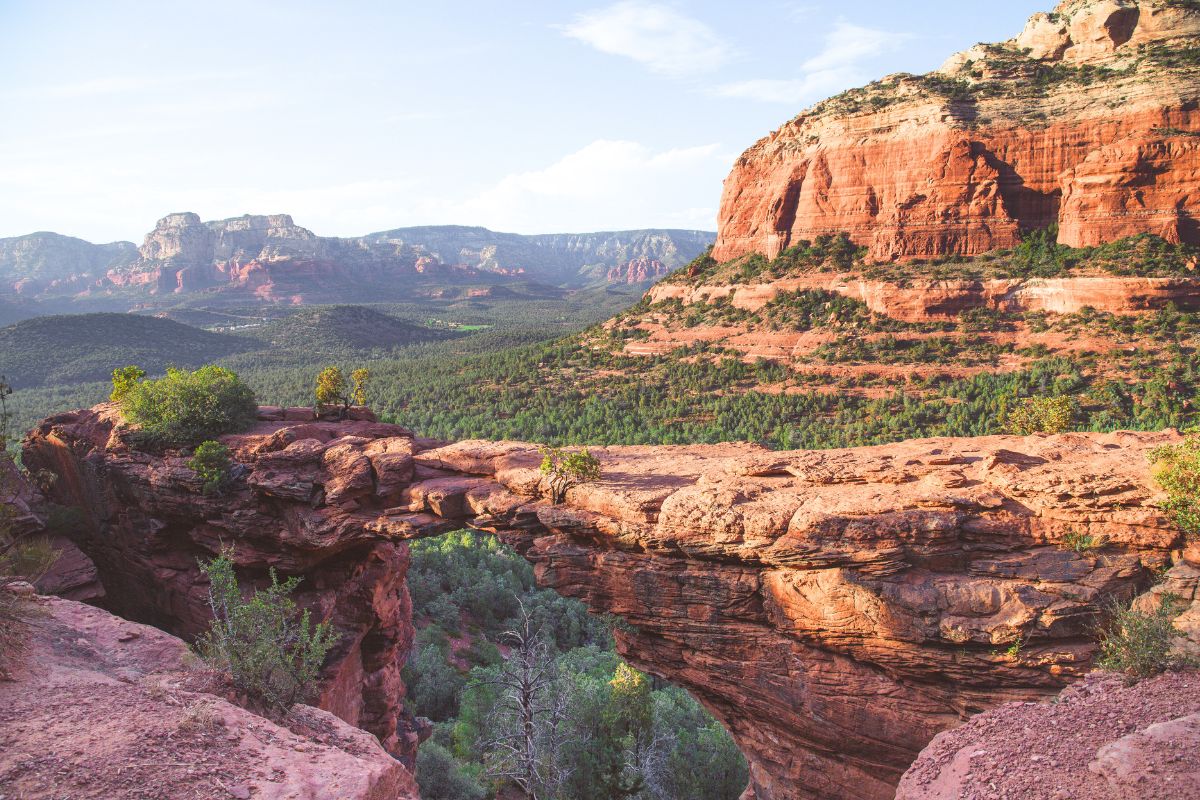 A breathtaking view of Devils Bridge Hike showcasing the iconic sandstone arch with the lush green valley and majestic red rock formations of Sedona in the background.