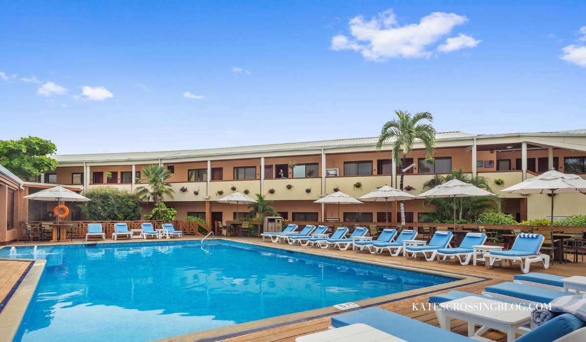 Picture of the pool at the best western. The pool is surrounded by a wooden deck and blue sun loungers with umbrellas. The two story hotel is in the back ground with balconies over looking the pool.