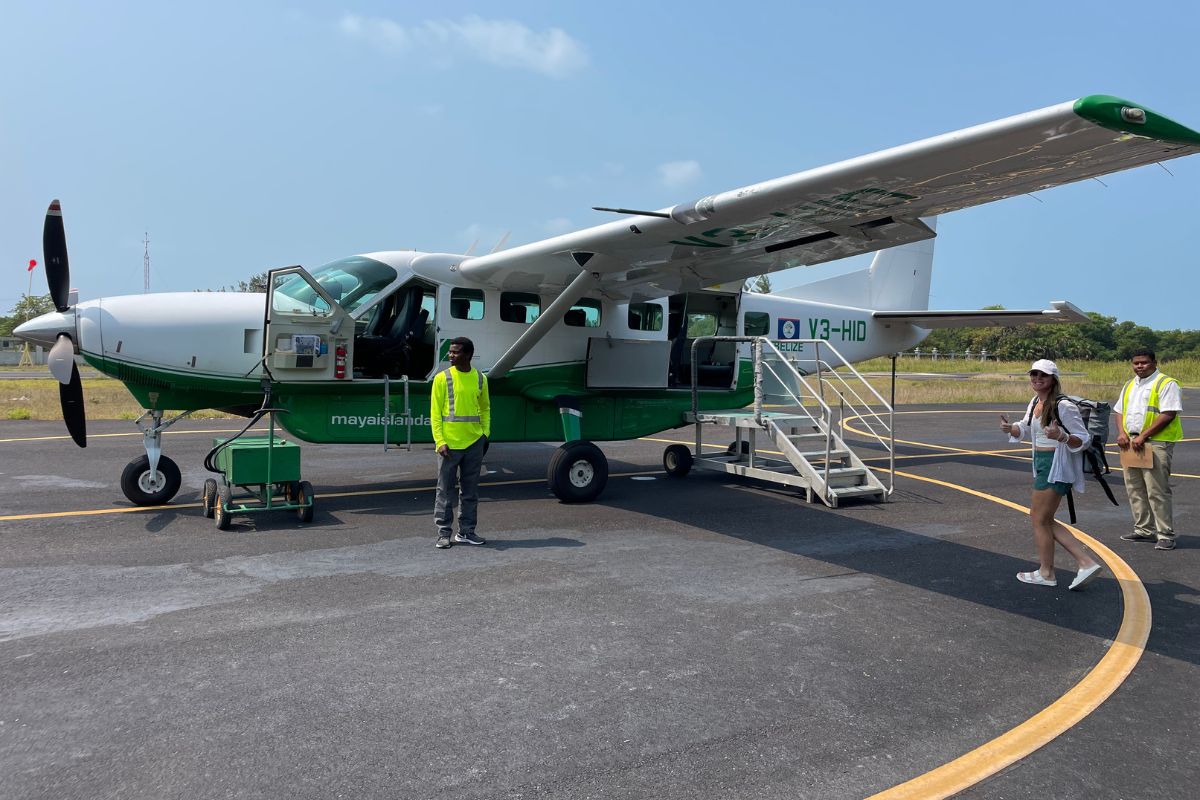 A small plane on the tarmac at Caye Caulker Airport with passengers and crew preparing for a flight.