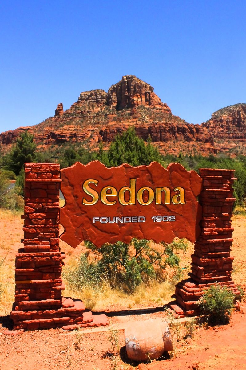 A welcome sign for Sedona with red rock formations in the background, perfect for starting your Sedona Day Trip adventure.