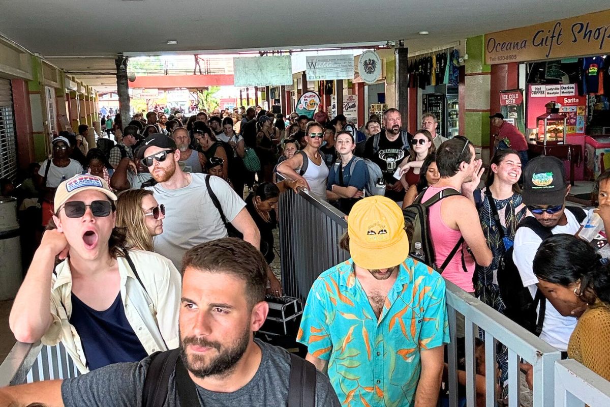 Crowded water taxi terminal in Belize City with many travelers waiting in line, carrying backpacks and luggage.