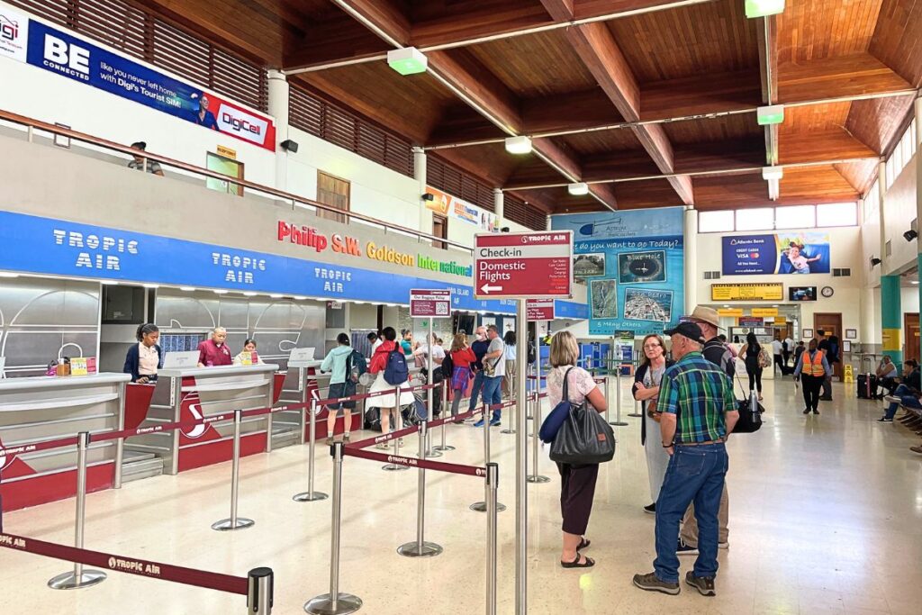 The domestic flight terminal at Belize City Airport, with passengers waiting in lines to check in.