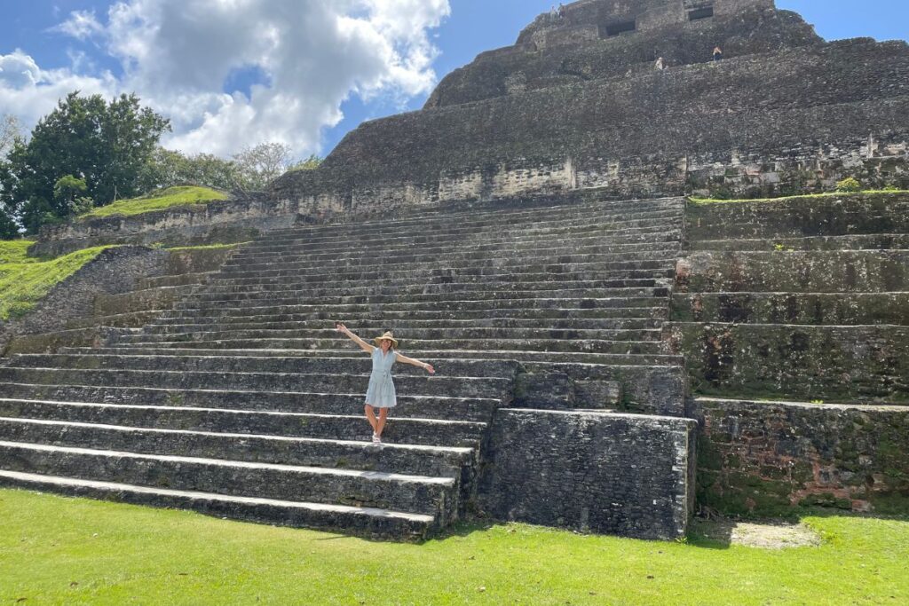 Woman standing on the steps of an ancient Mayan pyramid in Belize, showcasing a historical site included in the ultimate Belize travel guide.