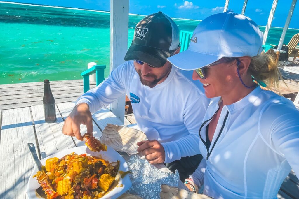 Kate and her husband enjoying a seafood meal on a deck by the turquoise waters in Belize.