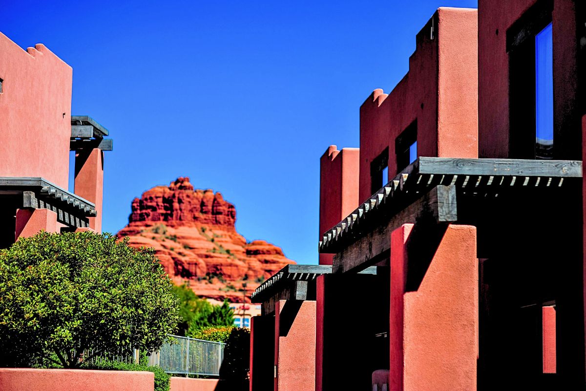 View of Bell Rock framed by the adobe-style architecture of Bell Rock Inn in Sedona, under a clear blue sky.