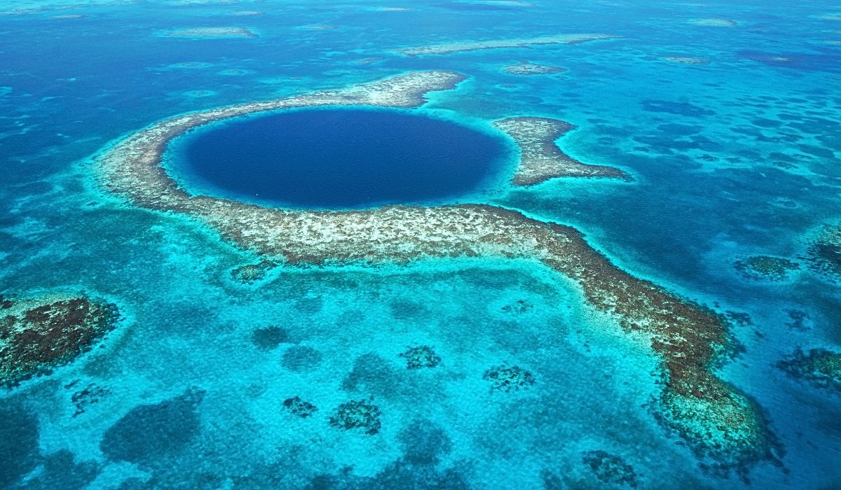 A stunning aerial view of the Great Blue Hole in Belize, a world-famous natural wonder surrounded by vibrant turquoise waters and coral reefs.