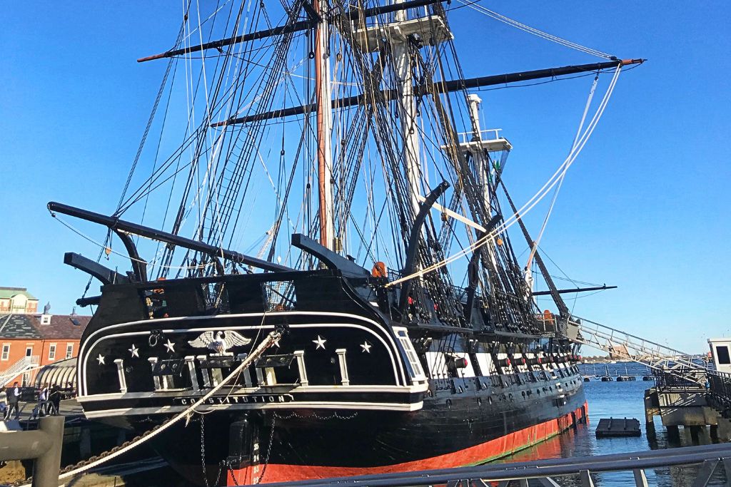 The USS Constitution, also known as 'Old Ironsides,' docked at the Charlestown Navy Yard in Boston. The historic warship, with its tall masts and rigging, is the oldest commissioned ship in the U.S. Navy, offering a glimpse into American naval history.