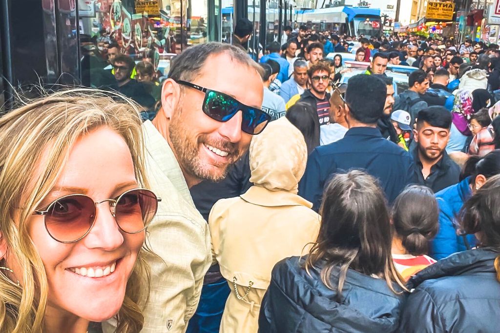 Kate and her husband smile amidst the bustling, crowded streets of Istanbul during the end of Ramadan celebrations. The streets are packed shoulder to shoulder with people, creating an atmosphere of chaos and energy as the crowd fills every available space, making it nearly impossible to move. The photo captures the intensity and vibrancy of this cultural moment.