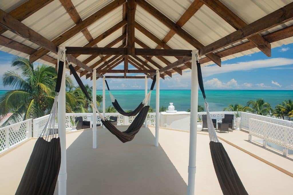 The rooftop lounge at Treetops Hotel in Caye Caulker, featuring hammocks under a shaded wooden pergola with stunning views of the turquoise Caribbean Sea. This serene spot is perfect for relaxation, with a breezy atmosphere and panoramic ocean scenery.