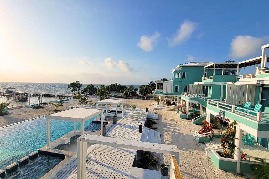 The scenic view from Island Magic Villas in Caye Caulker, showcasing turquoise-accented villas overlooking an infinity pool and the Caribbean Sea. The luxurious seaside setting includes spacious decks with pergolas and lounge areas, providing a relaxing atmosphere with direct beach access and breathtaking ocean views.