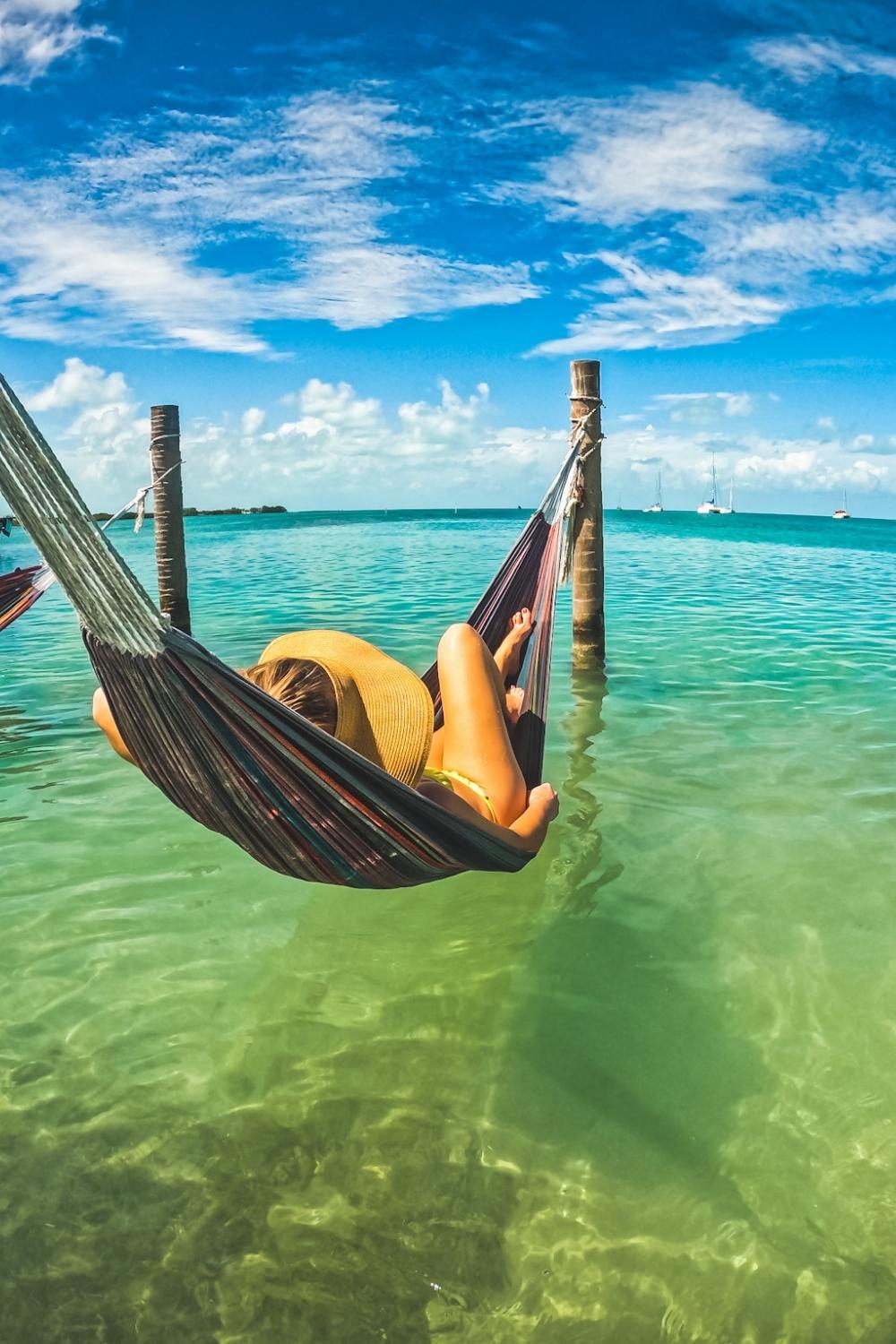 This photo shows Kate lounging in an over-water hammock with the turquoise caribbean waters stretching out to the horizon. 