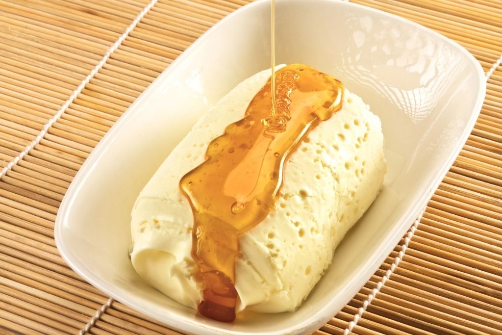 The image features a serving of traditional Turkish kaymak, a rich clotted cream, drizzled with golden honey in a white dish.