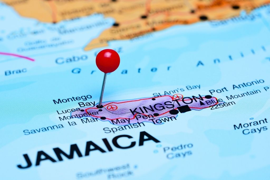 Close-up of a map of Jamaica with a red pushpin marking the island near Montego Bay and Kingston, highlighting key cities and geographical features in the Caribbean region.