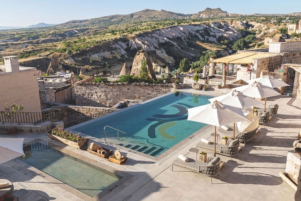 The terrace pool at Argos in Cappadocia features sun loungers, umbrellas, and sweeping views of the region’s signature rock formations—perfect for a luxury escape in a cave hotel.