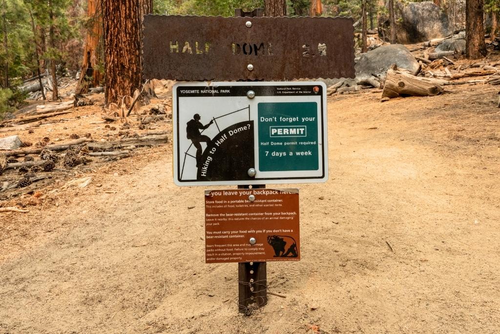 Trail sign at the start of the Half Dome hike in Yosemite, warning hikers to carry a permit and store food properly to avoid bear encounters.