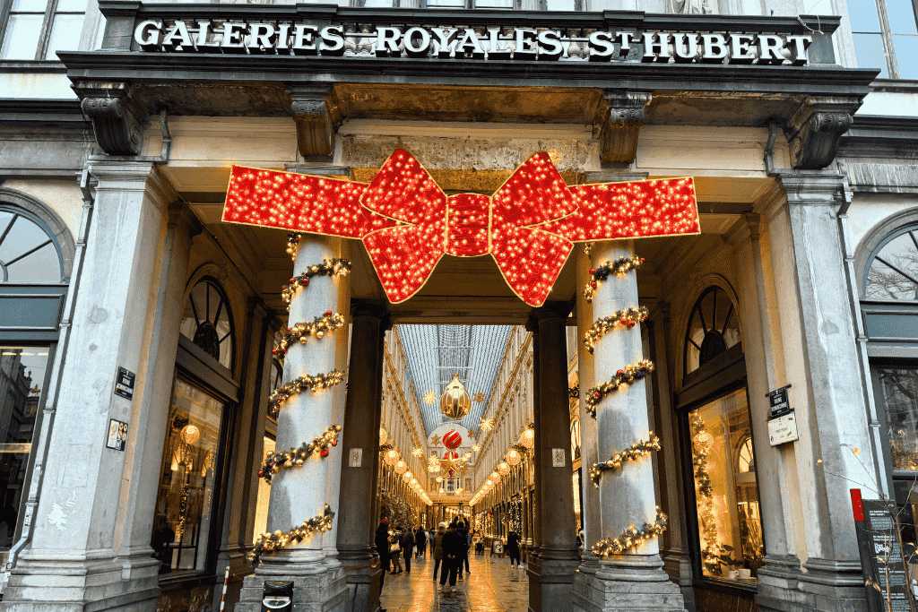 The entrance to Galeries Royales Saint-Hubert in Brussels is decked out for the holidays with garlands and a giant glowing red bow above the columns.