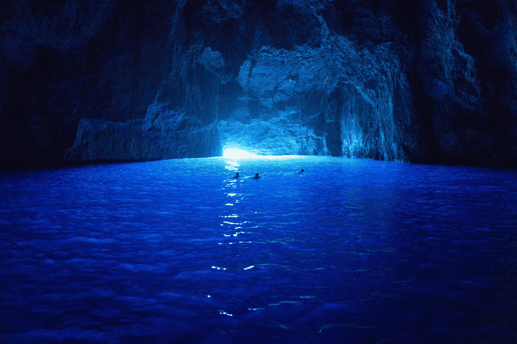 Swimmers float in the glowing sapphire waters of the Blue Grotto on Kastellorizo Island, where sunlight illuminates the sea cave’s rocky interior with an otherworldly blue hue.