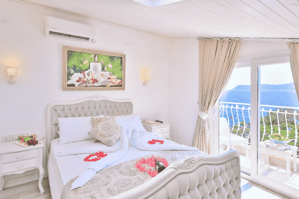 Romantic, light-filled hotel room in Kaş with swan towel art, floral accents, and a balcony overlooking the sea.