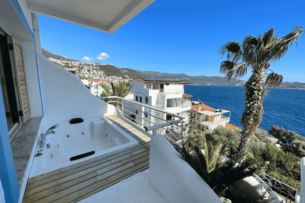 Hotel balcony in Kaş featuring a private jacuzzi with stunning views of the turquoise coastline and hillside homes.