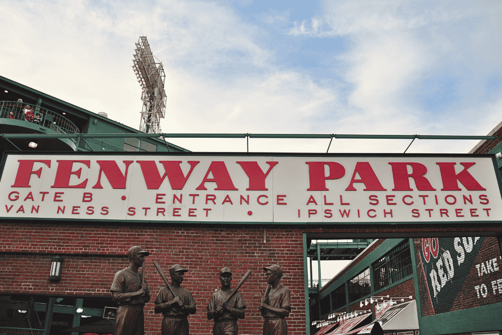 Fenway Park entrance sign with bold red lettering above Gate B, surrounded by statues of legendary Red Sox players and views of the stadium’s exterior. A must-see stop for baseball fans during a weekend getaway in Boston.