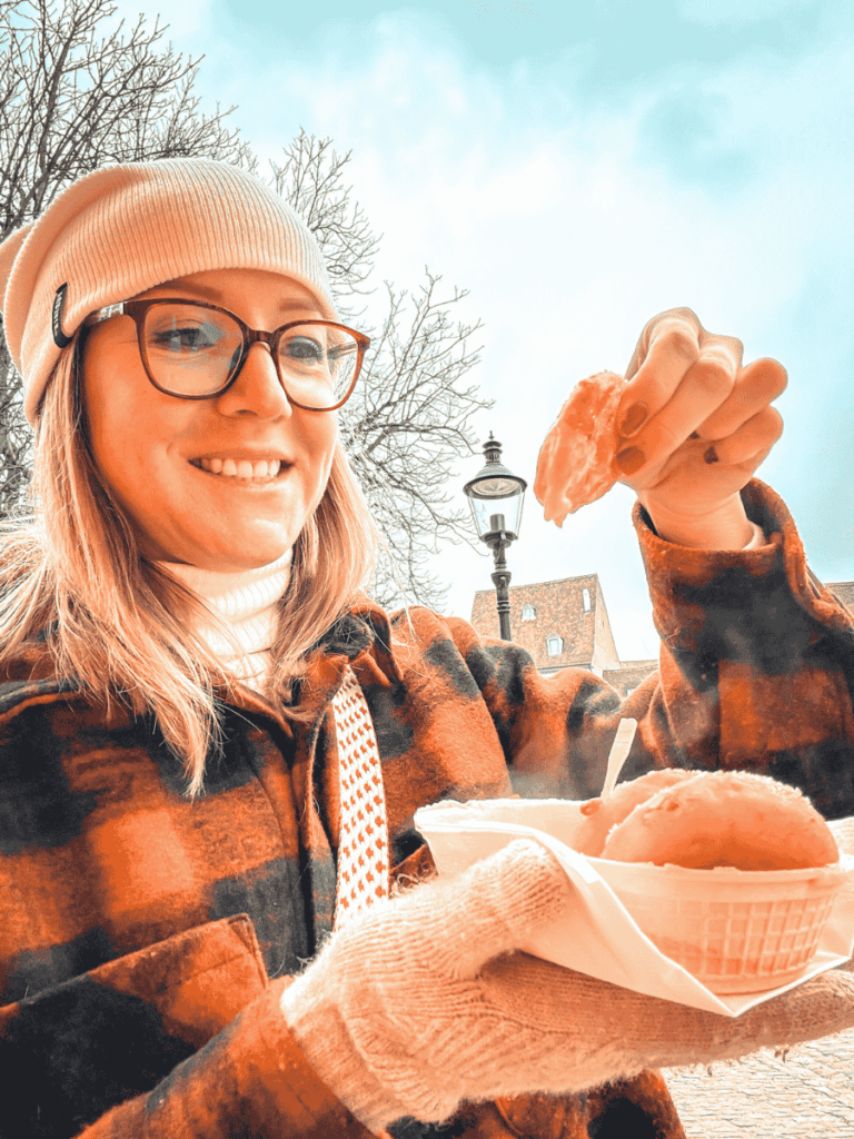 Kate smiles while holding a warm pastry at the Basel Christmas market.