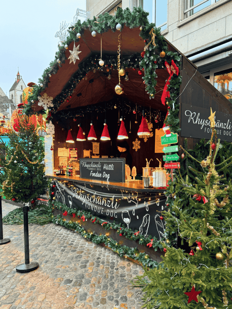A festive Christmas stall decorated with garlands sells fondue dogs in Basel.