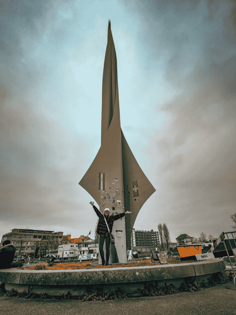 Kate poses with arms raised in front of the Dreiländereck monument in Basel.