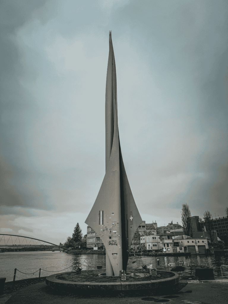 The Dreiländereck monument stands tall by the river where Switzerland, France, and Germany meet.