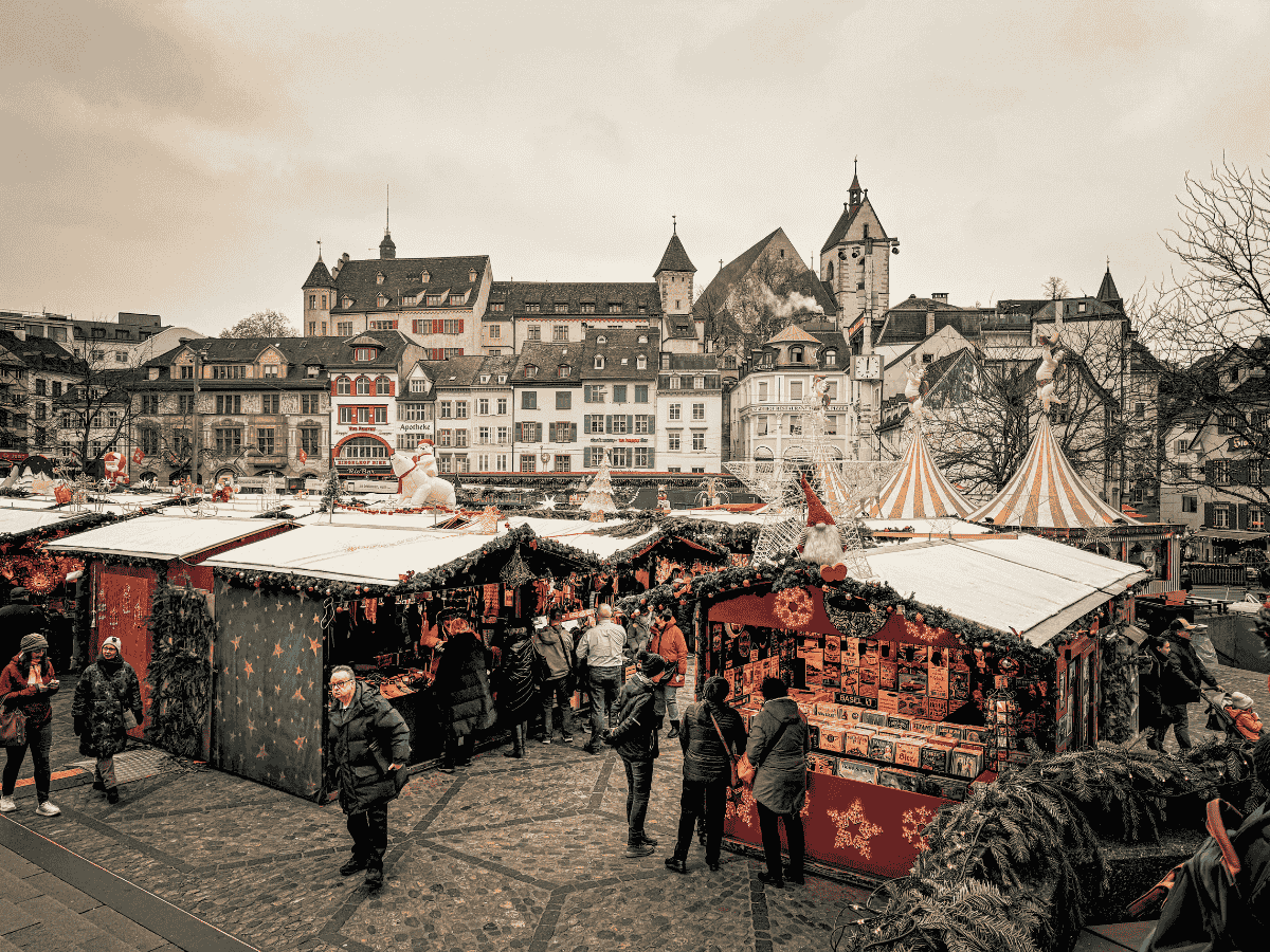 Festive wooden stalls and striped tents fill the bustling Basel Christmas market square.