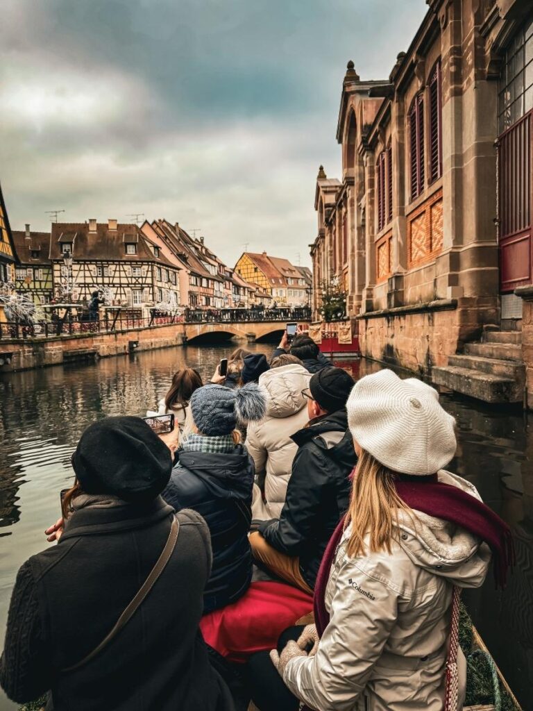 Tourists, including Kate, ride a boat through Colmar’s canal past colorful half-timbered houses.