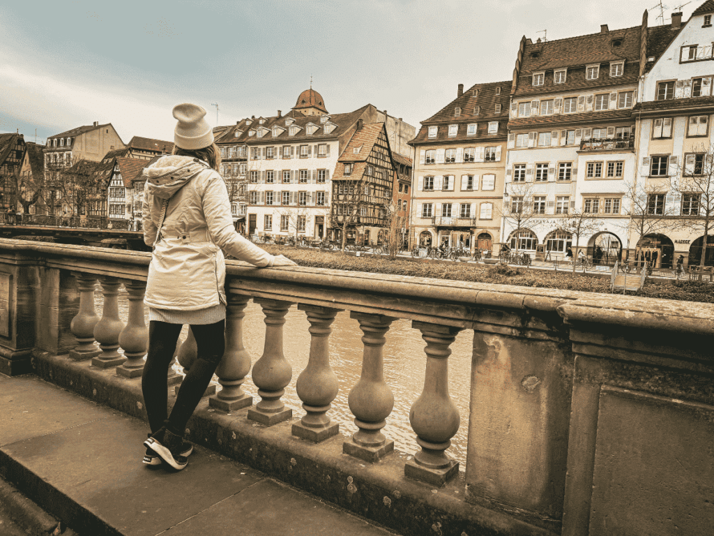 Kate looks out over the river in Strasbourg, admiring the row of historic half-timbered and stone buildings.
