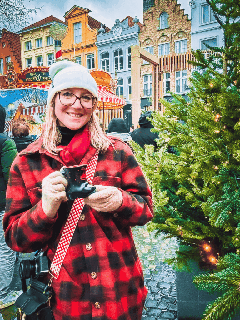 Kate smiles while holding a festive boot-shaped mug at the Bruges Christmas market.