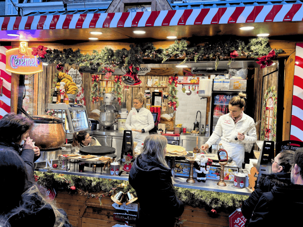 Vendors prepare crepes at a cozy Christmas market stall in Brussels.