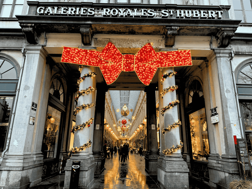 The entrance to the Galeries Royales Saint-Hubert is decorated with a giant illuminated red bow and Christmas garlands.