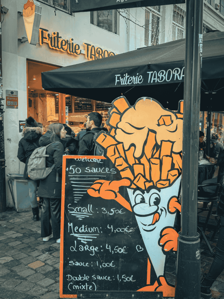 A colorful sign outside Friterie Tabora advertises fries with over fifty sauces.