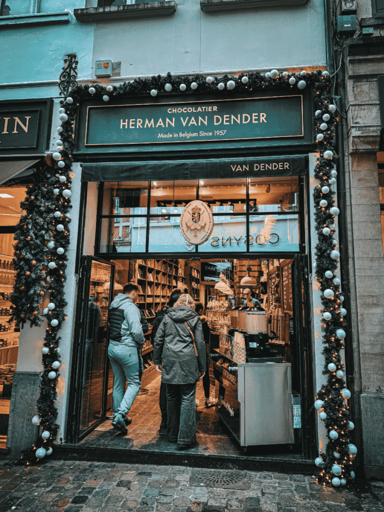 People enter the festive storefront of Herman Van Dender Chocolatier in Brussels.