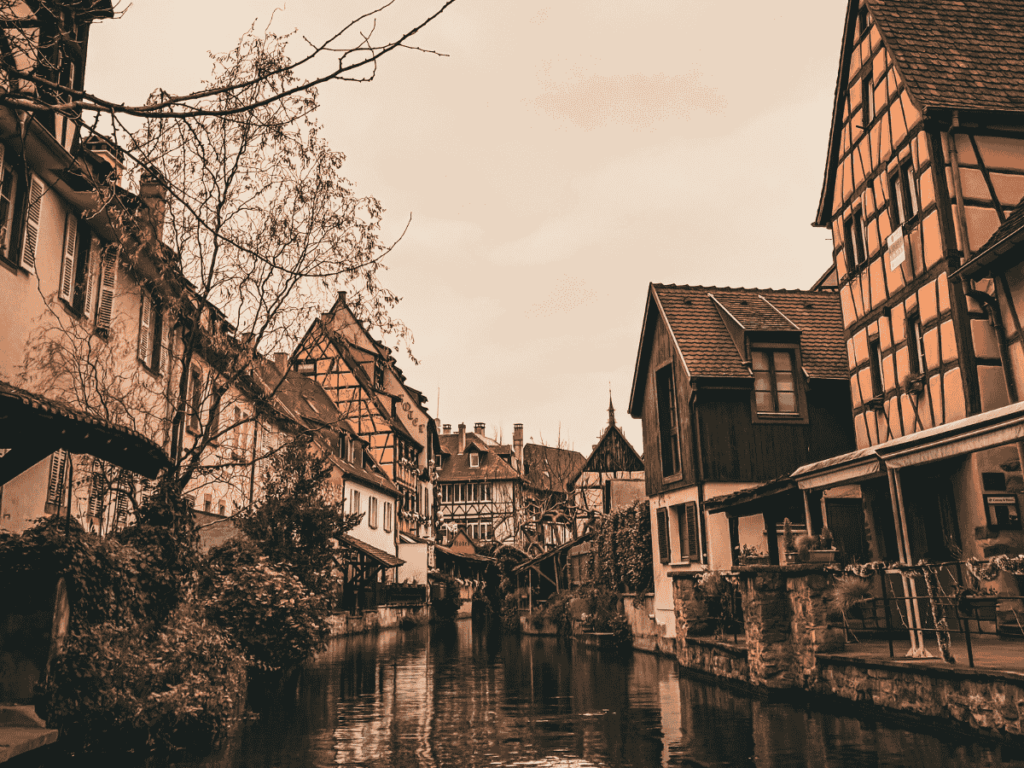 Canal view in Colmar’s Little Venice district with half-timbered houses reflecting on the water under a soft, overcast sky.