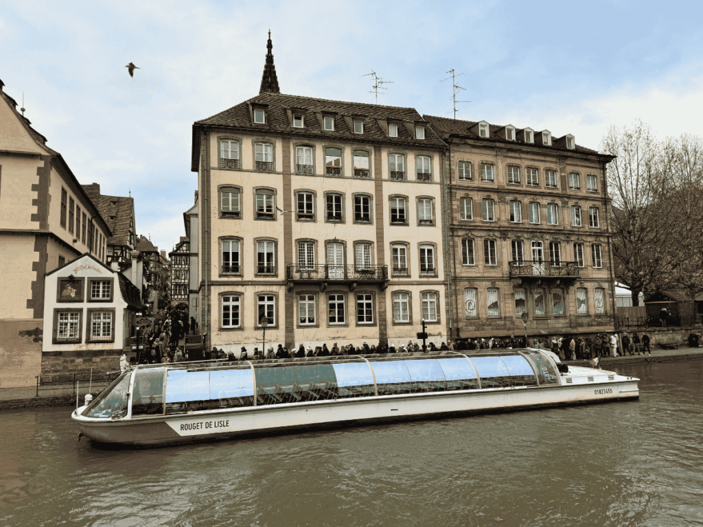 Glass covered river boat docked on the canals of Strasbourg as passengers board.