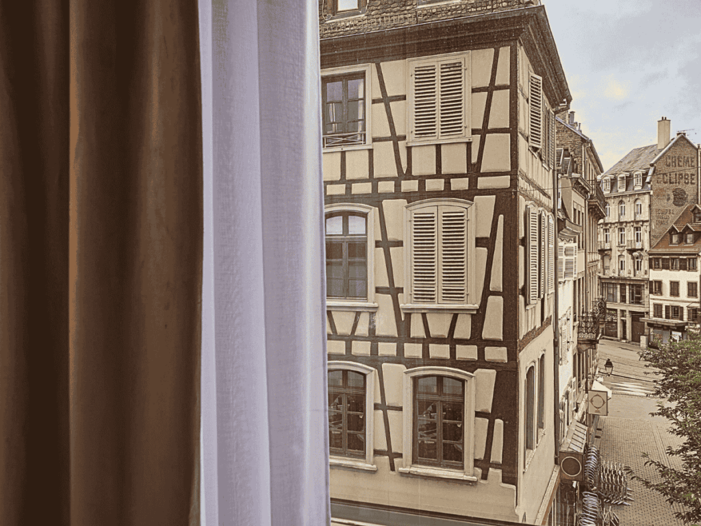 View from a hotel window at Hotel Kaijoo showing traditional half-timbered buildings and the quiet cobblestone streets of central Strasbourg.