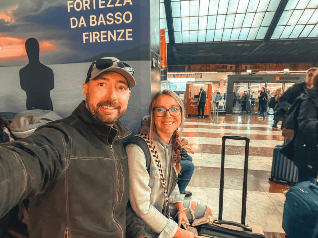 Kate and her travel companion sit with their luggage at Florence’s busy train station