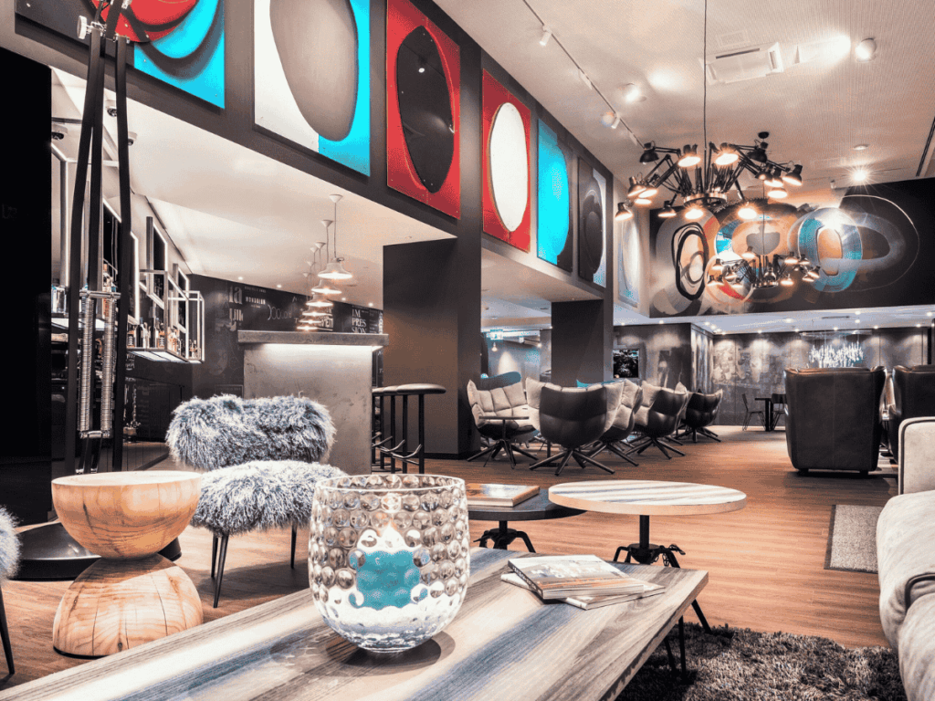 A stylish hotel lounge in Basel features modern art, eclectic furniture, and dramatic lighting in a spacious, open layout.