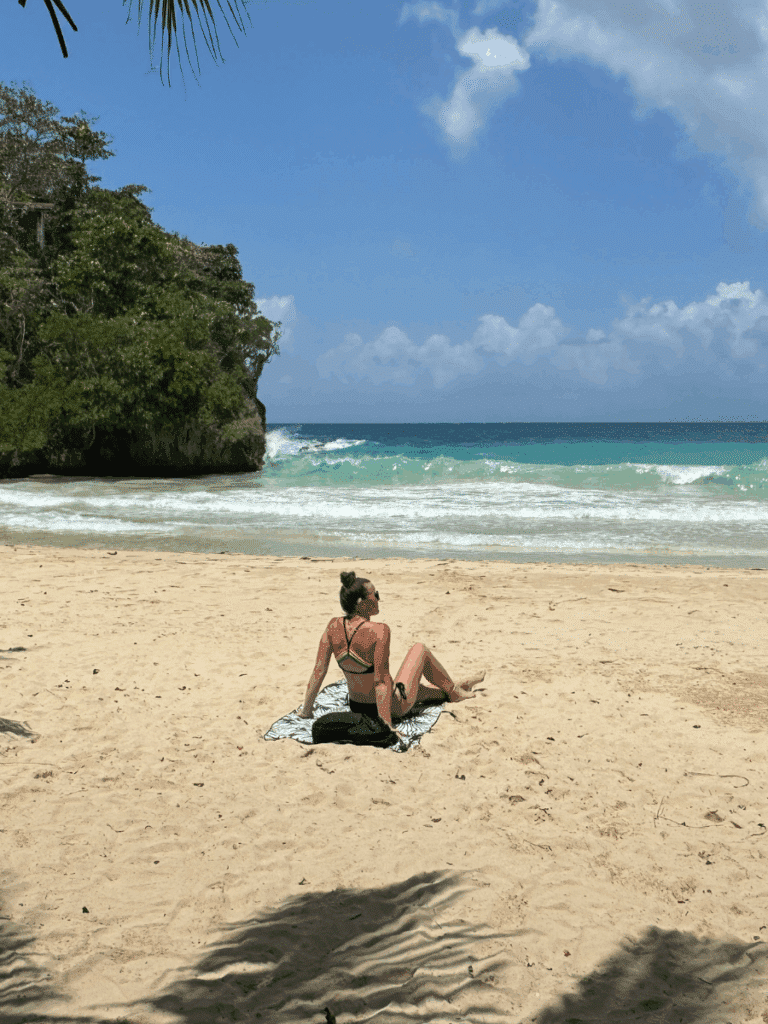 Kate relaxing on a wide, sandy beach while sitting on a patterned sand-free towel that keeps the surface clean and smooth beneath her
