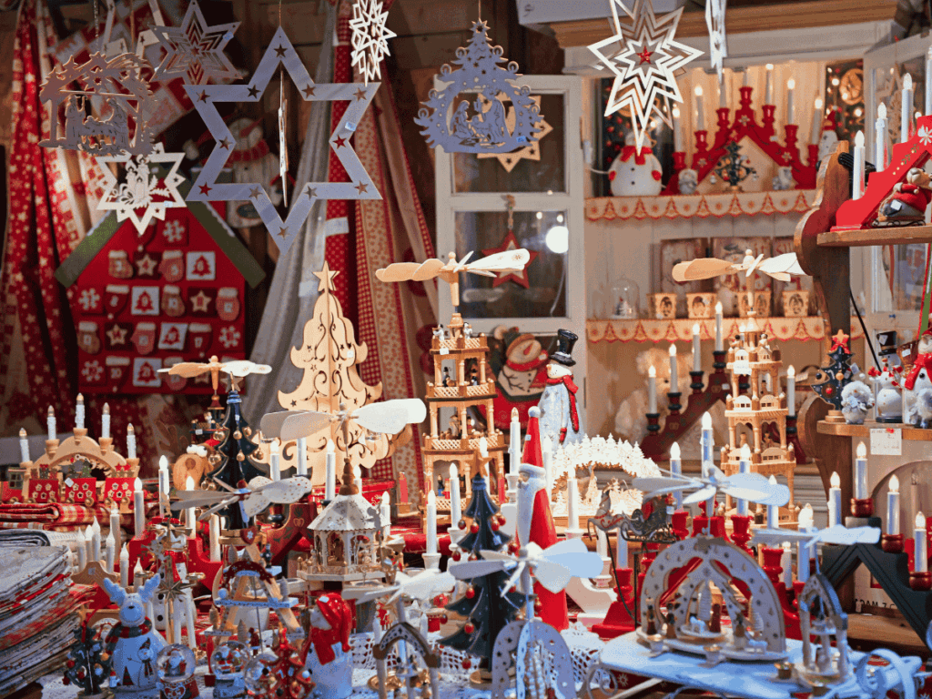 A cozy Colmar market stall is packed with handcrafted wooden Christmas decorations, candle arches, and festive figurines.