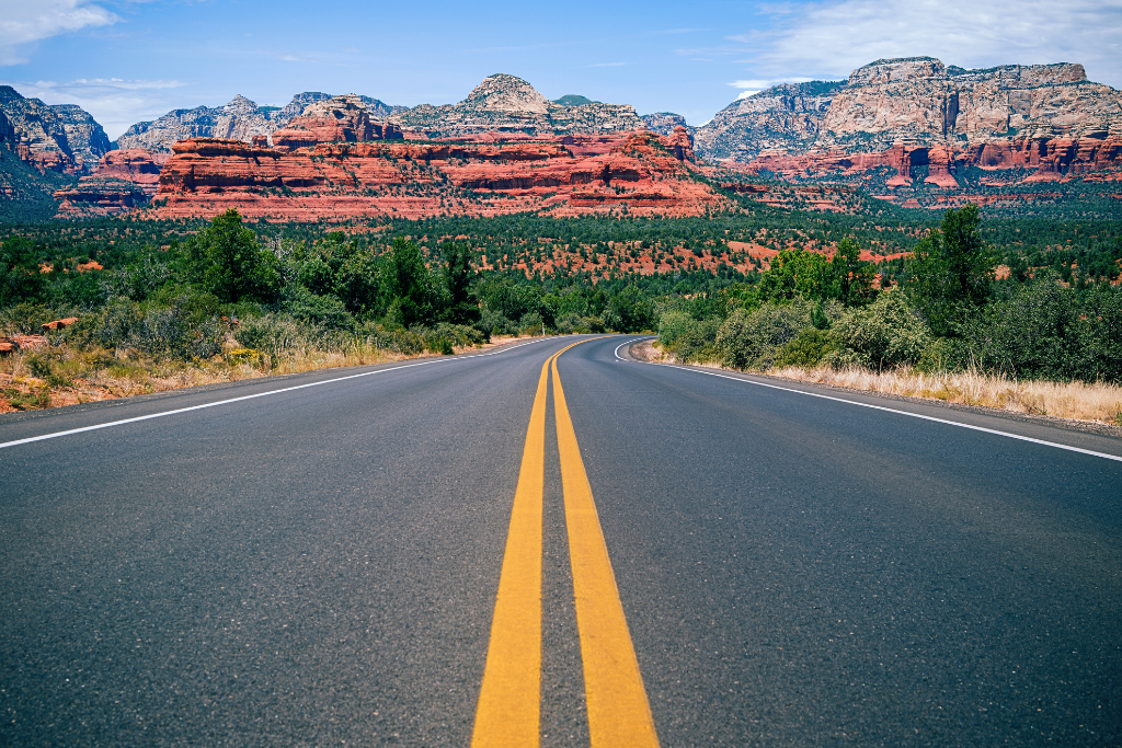 View of a two lane paved road cutting through the red rocks in Sedona.