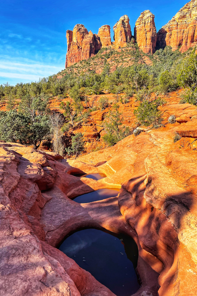 The seven sacred pools in the early morning sun with red rock spires in the background.
