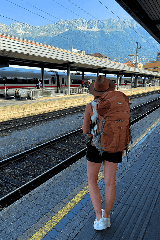 Kate standing at a train platform in Switzerland with her backpack on her back.