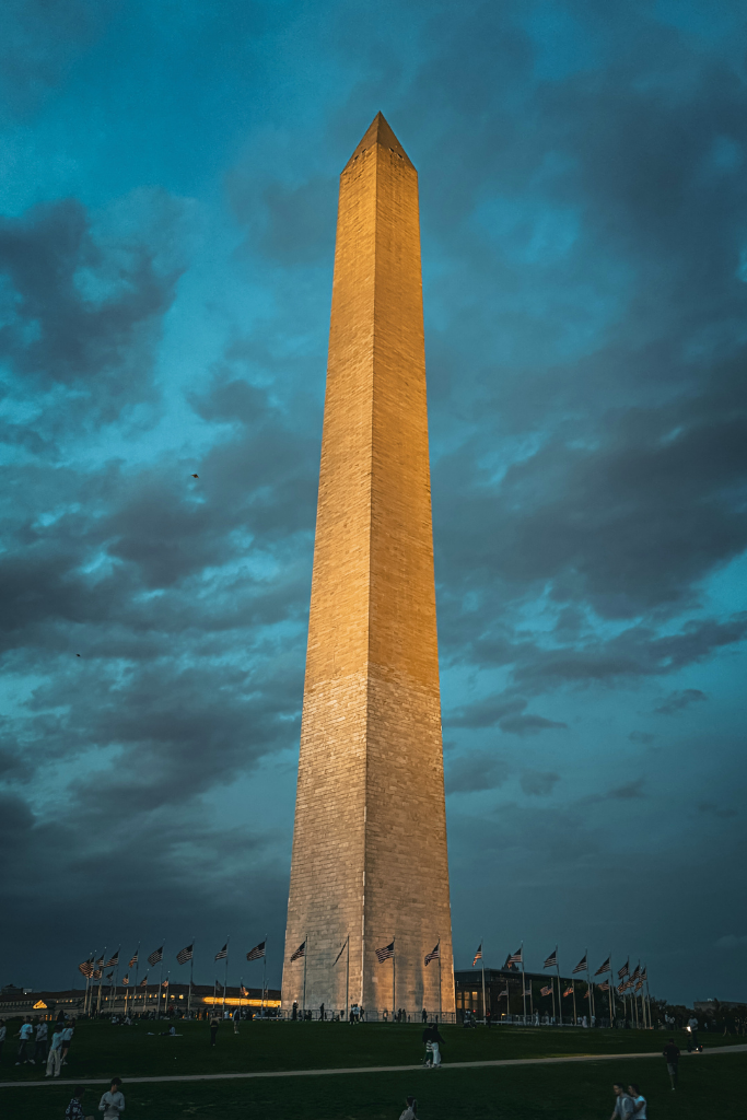 The washington monument lit up at night against a dark night sky.
